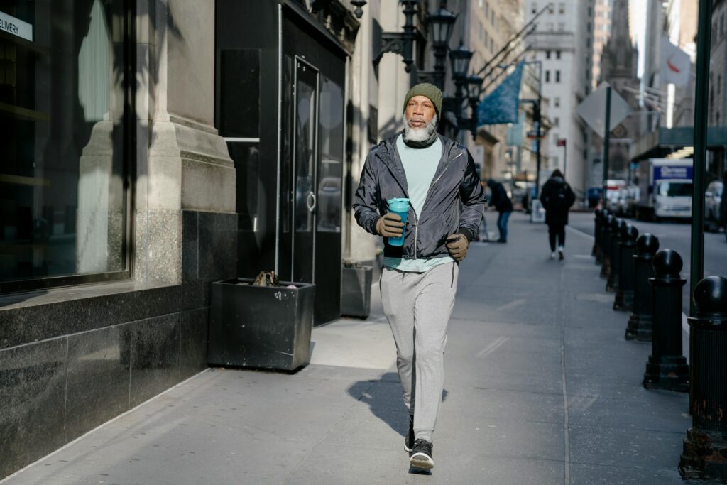 Man in a track suit walking through the street with a shaker bottle in his hand