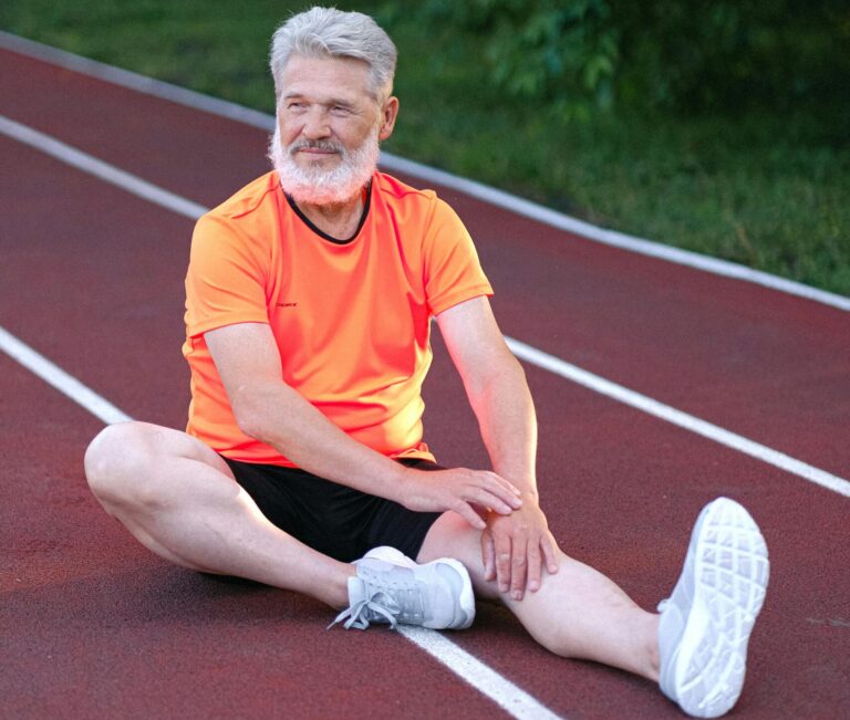 Old athletic men in an orange t-shirt stretching outside